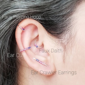 Puede incluir: Una oreja con varias piezas de joyer&iacute;a, incluyendo un aro de piercing falso, un ear cuff, un falso daith y pendientes trepadores. La joyer&iacute;a presenta una mezcla de plata y acentos coloridos. El texto dice: "Faux Piercing Hoop", "Ear Cuff", "Faux Daith" y "Ear Crawler Earrings".
