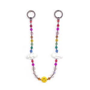 May include: A rainbow beaded chain with silver-tone rings at the top and a yellow smiley face charm at the bottom. White cloud charms are placed on each side of the chain. The beads are in various colors.