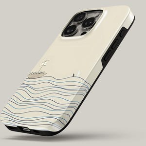 Può includere: Custodia per telefono color crema con un design nautico. Presenta una barca a vela e una persona sull'acqua, con linee ondulate blu e blu navy. La custodia ha un bordo nero e una finitura lucida.