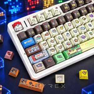 May include: A white mechanical keyboard featuring custom keycaps with various colorful character illustrations, Japanese characters, and game-themed icons. The escape key is red and white, while the spacebar displays a detailed landscape scene.