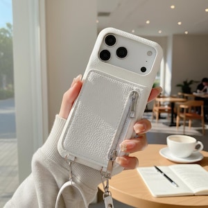 May include: White textured leather phone case with a zippered pocket and a wrist strap. The case has a white camera module and a silver zipper. The phone case is designed to protect the phone and carry small items.