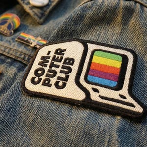 May include: Embroidered patch featuring a retro computer design with a rainbow-colored screen. The patch reads "COMPUTER CLUB" in black letters on a white background, outlined in black. Additional pins are visible on the denim jacket.
