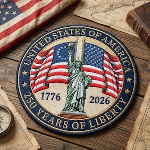 May include: Circular patch with a blue border and the text "UNITED STATES OF AMERICA" and "250 YEARS OF LIBERTY". The patch features the Statue of Liberty, American flags, and the years 1776 and 2026.