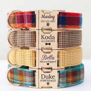 May include: Four personalized dog collars stacked vertically. Each collar features a different plaid or gingham pattern in red, brown, yellow, and teal. The gold-colored metal clasps are engraved with the dog's name, phone number, and other information.
