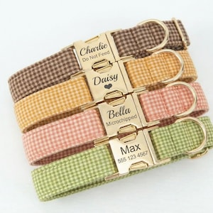 May include: Four personalized dog collars in brown, yellow, pink, and green gingham patterns. Each collar has a gold-colored buckle with a name and text engraved on it. The collars are stacked on top of each other.