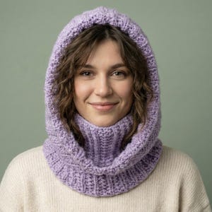May include: A lilac knitted hood and cowl set. The hood covers the head and neck, with a ribbed cowl. The knitwear is made of a soft, textured yarn, ideal for cold weather. The set is a cozy and stylish accessory. The cowl is designed to be pulled up.