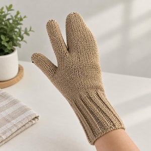 Può includere: Un guanto in maglia beige caratterizzato da un design a tre dita con un pollice separato e due sezioni per le dita unite. Il guanto è realizzato in filato testurizzato e presenta un polsino a coste che si estende fino al polso.