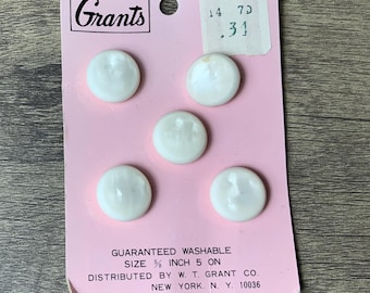 May include: A card with four white buttons on a pink background. The card has the text "Grants" and "No. 318" printed on it. The card also has the text "GUARANTEED WASHABLE SIZE 5/8 INCH 5 ON DISTRIBUTED BY W. T. GRANT CO. NEW YORK. N. Y. 10036" printed on it.