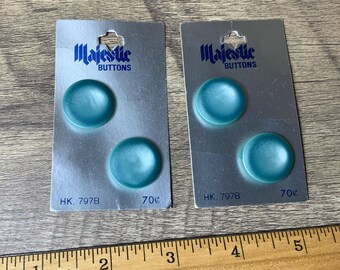 May include: Two cards of teal blue plastic buttons labelled "Majestic Buttons" with the price "70¢" printed on each card.
