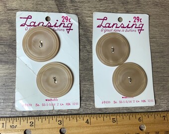 May include: Two cards each featuring two brown plastic buttons. The cards are labelled 'Lansing A Great Name in Buttons' and have the price '29c' printed on them. The cards also have the text '#8630 Sz. 55-1-5/16 2 Oz. HK 1241' and 'washable' printed on them.
