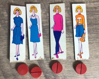 May include: Four vintage cardboard game pieces featuring illustrations of women in different outfits. Each piece has a red plastic token with a line through it.