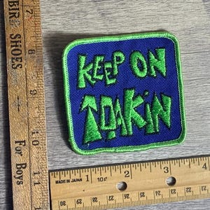 May include: Green and blue embroidered patch with the text "Keep on Tokin'" in a stylized font.