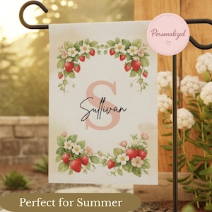 May include: A personalized garden flag with a strawberry and floral design. The flag features the name "Sullivan" in a script font, with a large pink letter "S". The flag is decorated with red strawberries, white flowers, and green leaves. The text "Personalized" is on a pink circle.