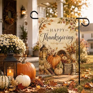 May include: A rectangular garden flag featuring the text Happy Thanksgiving in elegant script. The design displays a harvest scene with orange pumpkins, a lit lantern, a woven basket, and autumn foliage in shades of gold, brown, and red.