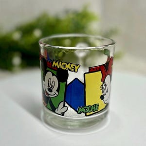 Peut inclure: Verre transparent avec Mickey et Minnie Mouse. Le verre pr&eacute;sente un design color&eacute; avec les mots "Mickey Mouse". Le design comprend des accents verts, jaunes, bleus et rouges. Un ajout amusant &agrave; la collection de tout fan de Disney.