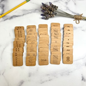 May include: Wooden number tiles with different representations of numbers 1 through 8. The tiles show the number, the number written out, tally marks, dots, and fingers.