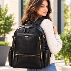 May include: A black backpack featuring gold-tone metal zippers, a top handle, and adjustable shoulder straps. The bag includes a front zippered pocket, side elasticized pockets, and a small rectangular gold-tone metal plate on the front.