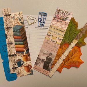 May include: A collection of decorative bookmarks, paper clips, and leaf-shaped cutouts. The bookmarks feature bee illustrations, stacks of books, and vintage imagery. One bookmark reads "Order No. 17" and "&frac12; teaspoonful".