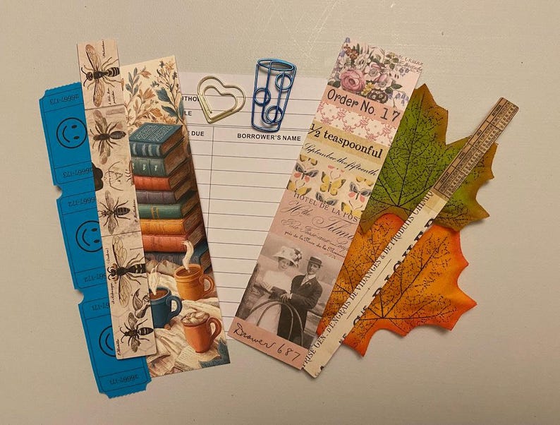 May include: A collection of decorative bookmarks, paper clips, and leaf-shaped cutouts. The bookmarks feature bee illustrations, stacks of books, and vintage imagery. One bookmark reads "Order No. 17" and "&frac12; teaspoonful".