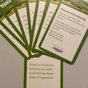 May include: A collection of green and white cards with the words "Small Moments" and "Moments With Meaning." The cards feature prompts to recall memories and write about them. The bottom card asks, "What's an ordinary moment you wish you'd written down when it happened?"