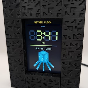May include: A digital clock with a black, textured, block-patterned frame. The screen displays the text NETHER CLOCK, FRIDAY, PM, JUN 05 2026, a digital time readout, and a graphic of a blue, multi-legged creature from a video game.