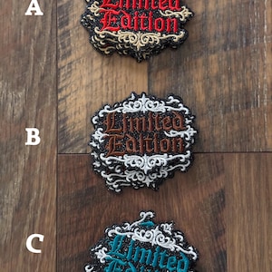 May include: Three embroidered patches with the words "Limited Edition". Each patch has a different color scheme: red and gold, brown and white, and teal and white. The patches have a decorative border.