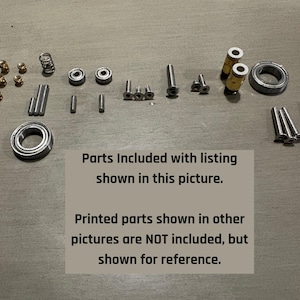 May include: An assortment of small metal parts, including bearings, screws, and pins, are arranged on a light gray surface. The text on the image states, "Parts Included with listing shown in this picture."