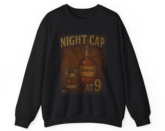 Może przedstawiać: Czarna bluza z nadrukiem butelki bourbonu i szklanki whisky z lodem. Grafika zawiera napisy "NIGHT CAP" nad butelką i "BOURBON" na butelce, z "AT 9" poniżej.