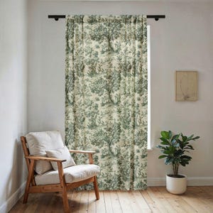 Könnte beinhalten: Grün-cremefarbener Vorhang mit Toile-de-Jouy-Muster, das Bäume, Tiere und Figuren zeigt. Der Vorhang hängt an einer schwarzen Stange vor einem Fenster. Links steht ein Holzstuhl mit cremefarbenem Kissen und Kissen.