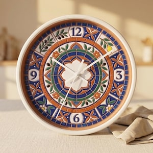 May include: A round wall clock with a white frame and a decorative face. The clock face features a colourful mosaic design with blue, orange, and green patterns, and white clock hands. The numbers 3, 6, 9, and 12 are visible.