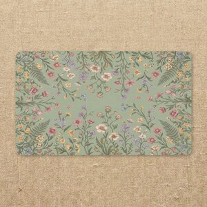 May include: Rectangular floral design on a light green background. The design features a variety of flowers in shades of pink, purple, yellow, and white, with green leaves and stems. The corners are rounded.