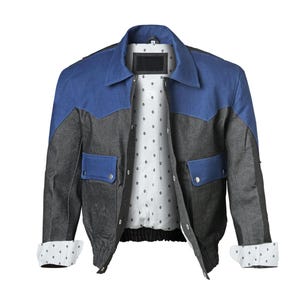 Puede incluir: Chaqueta vaquera de dos tonos con canesú y detalles de bolsillo azules y cuerpo gris. La chaqueta presenta una etiqueta negra, dos bolsillos delanteros y un forro blanco estampado. Los puños están doblados, revelando el forro estampado.