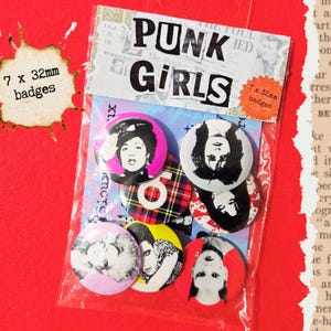 Peut inclure: Un ensemble de sept badges ronds de 32 mm étiquetés Punk Girls dans un sachet plastique transparent. Les badges présentent des portraits en noir et blanc, un motif écossais rouge, noir et blanc, et des fonds unis en rose, jaune et rouge.