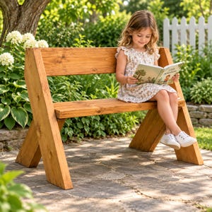 Puede incluir: Un banco de madera natural con un diseño de patas en forma de A inclinada y un respaldo horizontal. El banco está construido con tablones de madera gruesos y teñidos con un patrón de veta visible, con una estructura simple y robusta.
