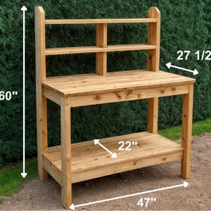 May include: A wooden potting bench with a natural finish. It features a top work surface, a lower shelf, and an upper shelf with two compartments. The bench is 60 inches tall, 47 inches wide, and 27.5 inches deep, with a 22-inch shelf.