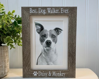 May include: A rustic wood picture frame with a black and white photo of a dog inside. The frame has the text "Best. Dog. Walker. Ever." at the top and "Daisy & Monkey" with a paw print at the bottom.