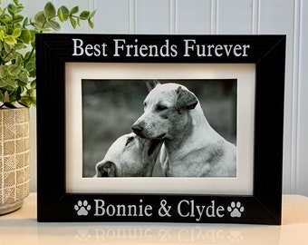 May include: Black wooden picture frame with the text "Best Friends Furever" at the top and "Bonnie & Clyde" with paw prints on the bottom. A black and white photo of two dogs is in the frame.