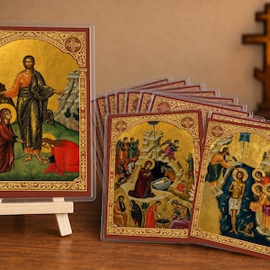Puede incluir: Una colección de iconos religiosos rectangulares con fondos de pan de oro y escenas bíblicas detalladas. Cada icono está en una funda protectora transparente, uno se muestra en un pequeño caballete de madera y los demás están desplegados.