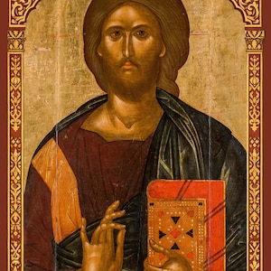 Puede incluir: Un icono religioso que muestra una figura central con cabello largo casta&ntilde;o y barba, vistiendo una capa azul oscuro sobre una t&uacute;nica granate. La figura sostiene un libro rojo con detalles dorados y hace un gesto con la mano. El borde es dorado.