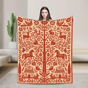 May include: A rectangular throw blanket featuring a cream-colored background with a symmetrical, intricate pattern in burnt orange. The design depicts a central tree surrounded by horses, deer, rabbits, birds, houses, and floral motifs.