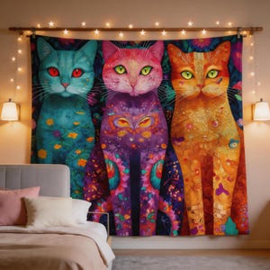 May include: A colorful tapestry featuring three stylized cats. The cats are depicted in vibrant hues: teal, pink, and orange, each with unique patterns and eye colors. The background is a dark floral design, and the tapestry is hung with decorative lights.