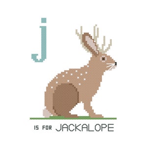 May include: A light blue letter J with a brown jackalope with antlers sitting on green grass. The text "J is for Jackalope" is below the image.