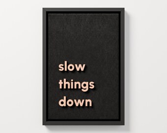 3D-Wandbild „Slow Things Down“, zarte aprikosenfarbene Buchstaben auf schwarzem Stoff, gerahmte Typografie