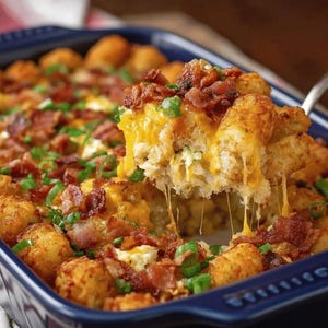 Pode incluir: Uma ca&ccedil;arola assada em um prato azul, com tater tots dourados, queijo cheddar derretido, bacon esfarelado e cebolinha picada. Uma por&ccedil;&atilde;o &eacute; levantada com um utens&iacute;lio para servir, mostrando as camadas de queijo e saborosas.