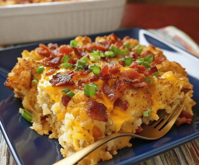 Pode incluir: Uma por&ccedil;&atilde;o de ca&ccedil;arola dourada, coberta com queijo derretido, peda&ccedil;os de bacon e cebolinhas picadas. Um garfo dourado repousa sobre um prato quadrado azul, pronto para servir.