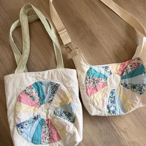 May include: Two off-white fabric bags featuring a circular patchwork design made of multi-colored floral and solid pastel fabric segments. One bag is a tote with light green handles, and the other is a shoulder bag with a long adjustable strap.