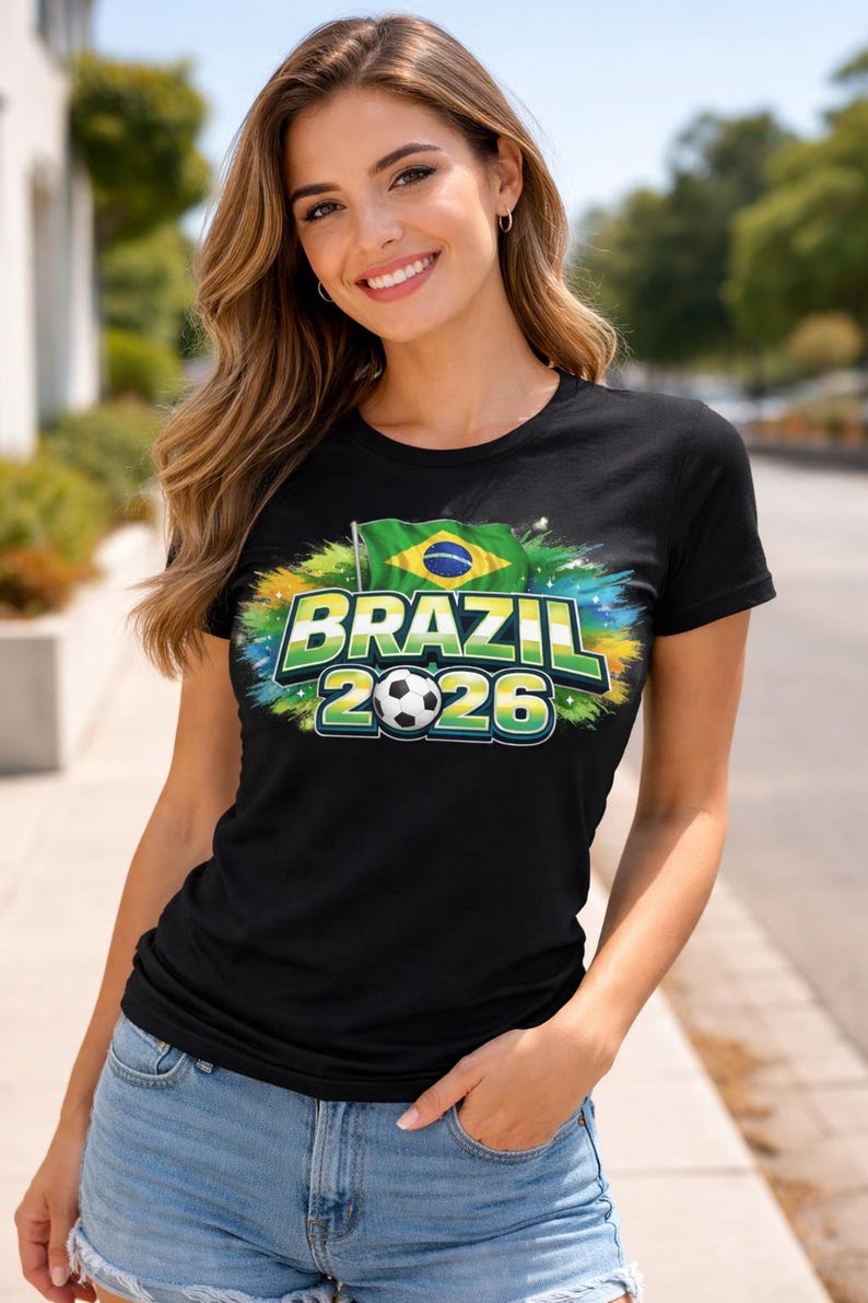 May include: Black t-shirt featuring a Brazil 2026 design. The graphic includes the Brazilian flag, a football, and the text "BRAZIL 2026" in green and blue. The shirt is worn by a person.