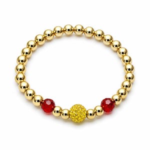 May include: Gold beaded bracelet with a central yellow crystal ball and two red crystal beads. The bracelet is made of small, round, gold-colored beads. The design is simple and elegant.