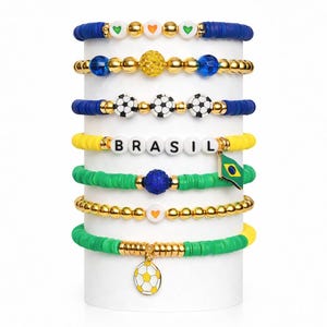 May include: A white ceramic mug with a black handle and the text "But First, Coffee" in a bold, black font. The mug is set against a blurred background, suggesting a cozy setting.