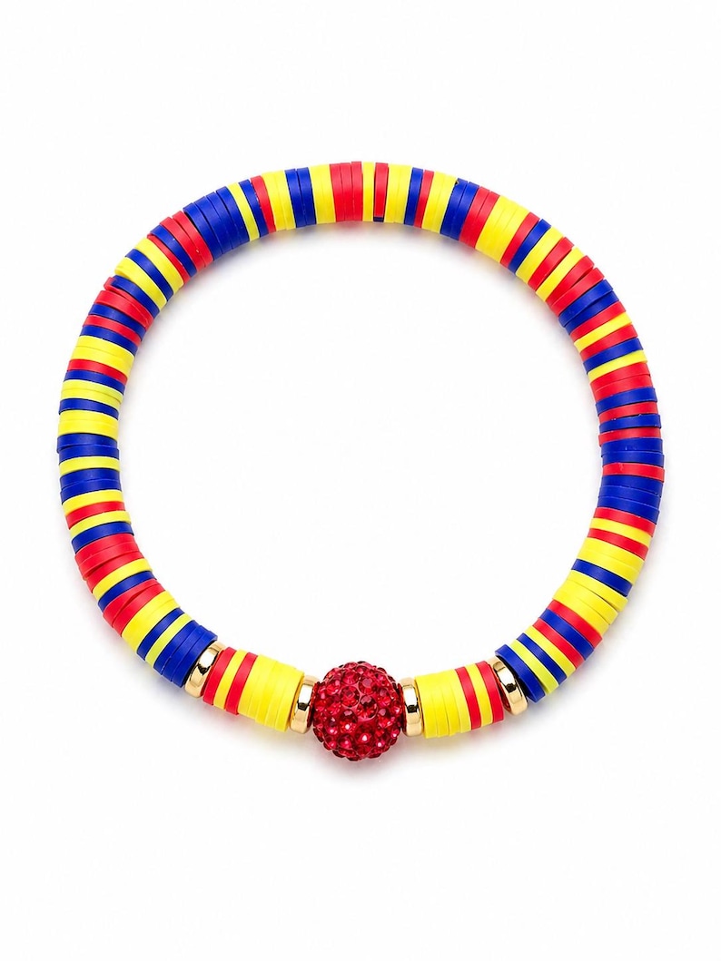 May include: A colorful bracelet featuring alternating red, yellow, and blue disc-shaped beads. A central red, crystal-studded ball is accented with gold-colored metal rings. The bracelet is designed to be worn around the wrist.